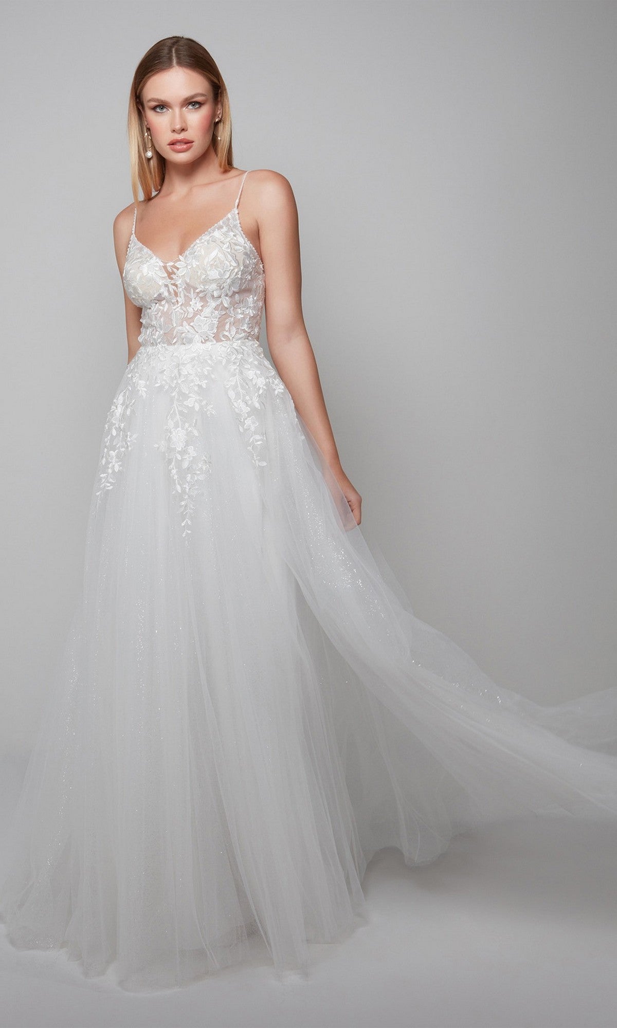A woman in the Alyce 7079 long white dress, featuring a sleeveless lace bodice and flowing tulle skirt, exudes bridal elegance against a plain light gray background.